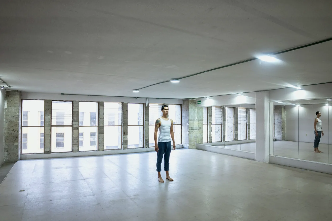 A large studio with tall windows and a mirror wall