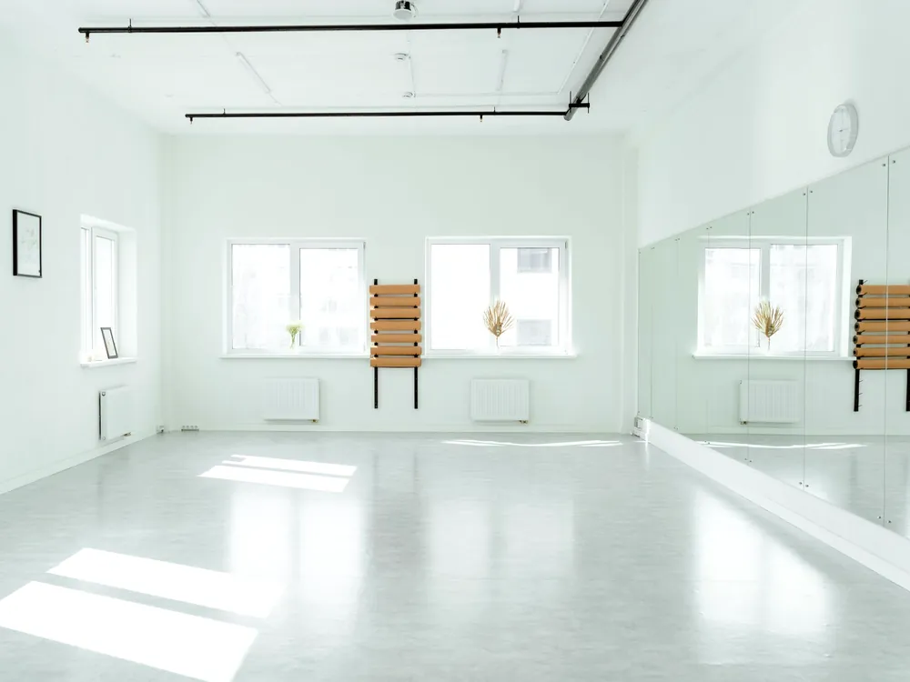 The corner of an empty studio where the mirror meets the windows