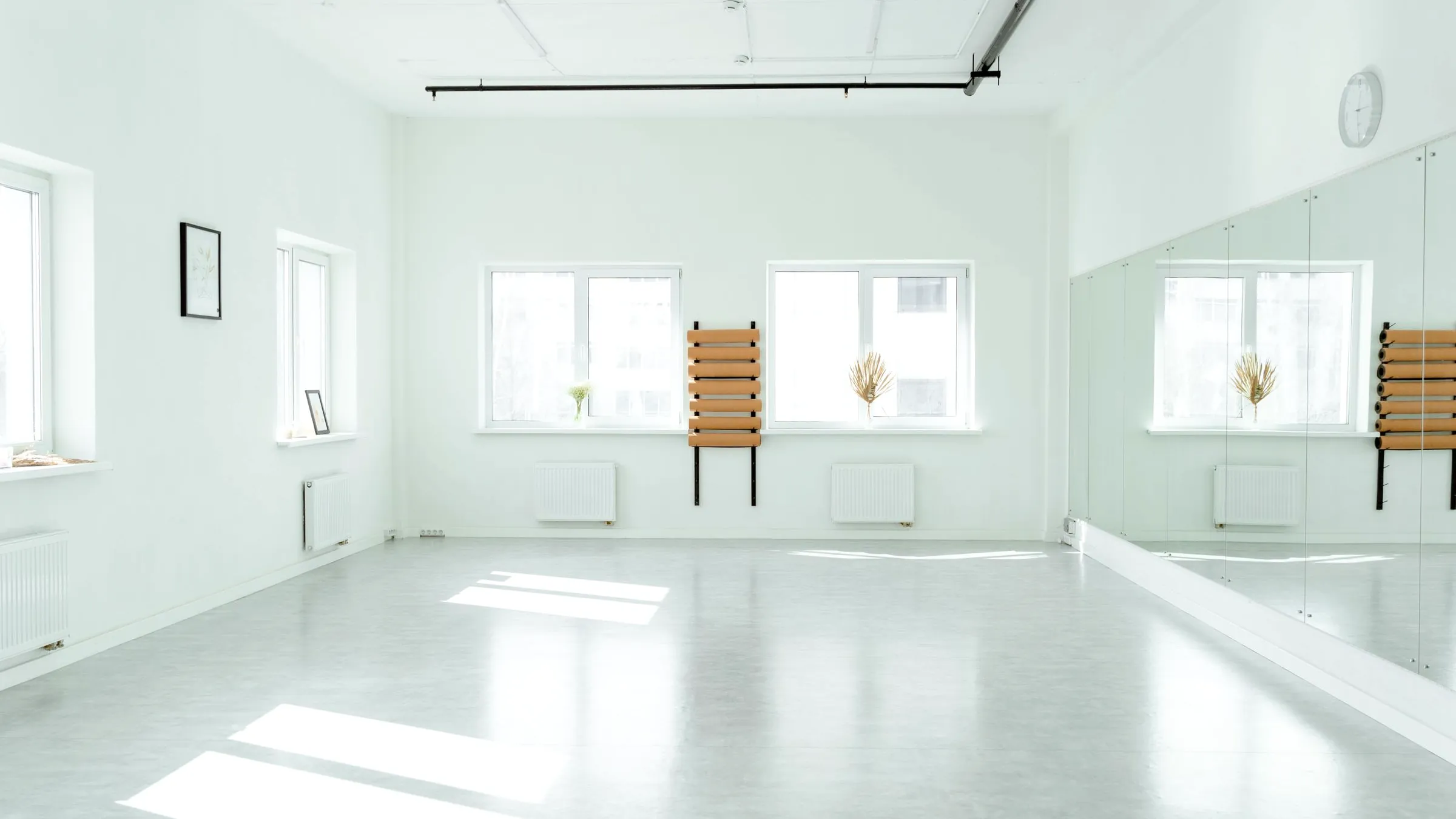 A bright empty dance studio with a mirror wall and wall barres
