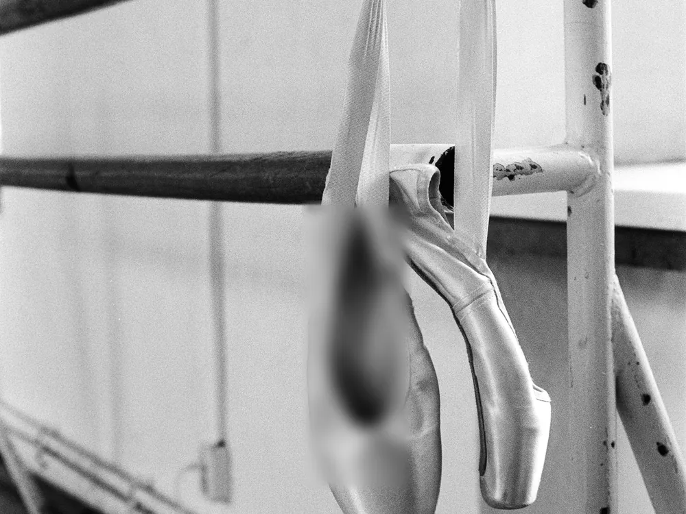 Pointe shoes hanging from a barre