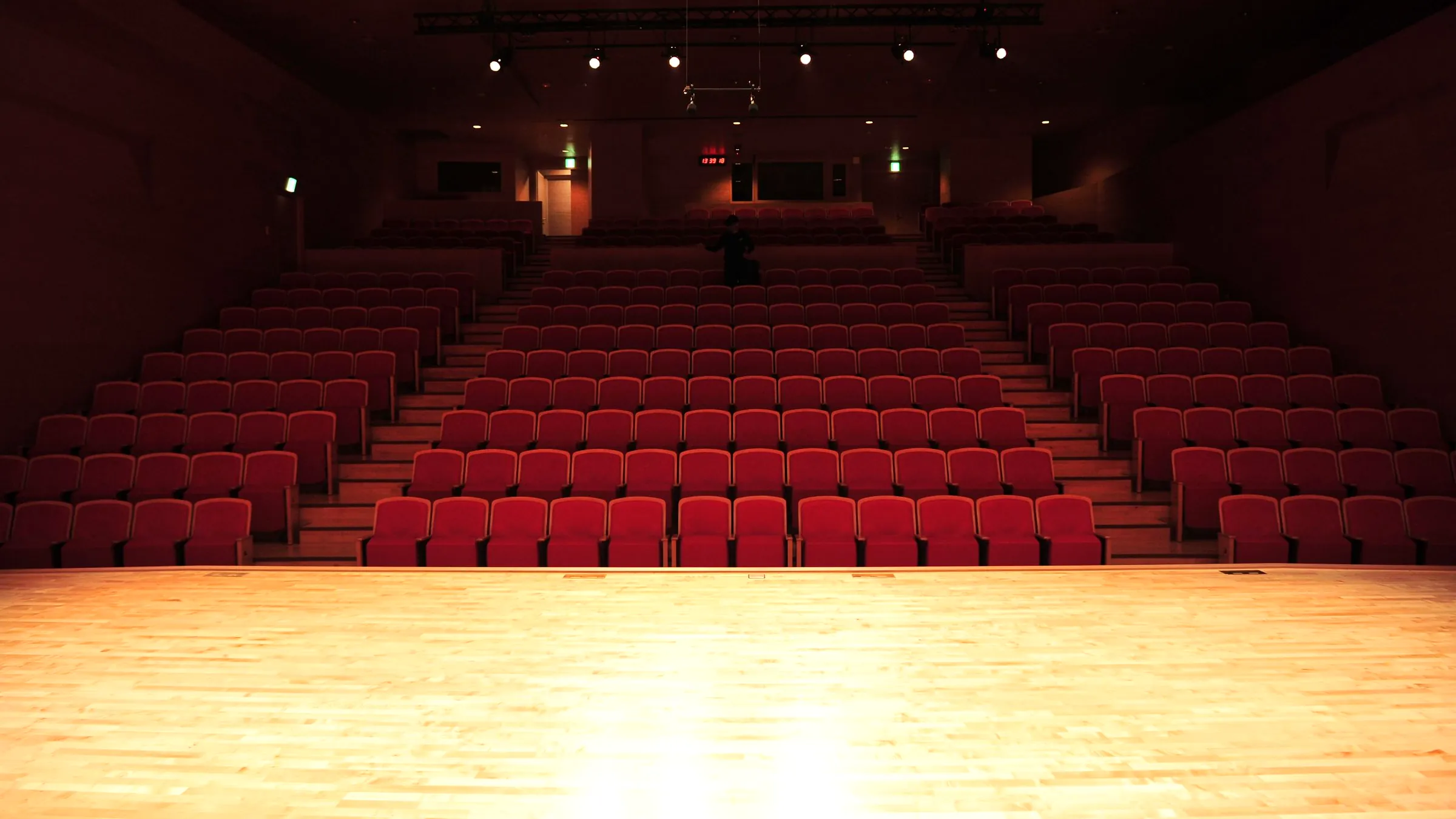 An empty auditorium seen from a lit wooden stage
