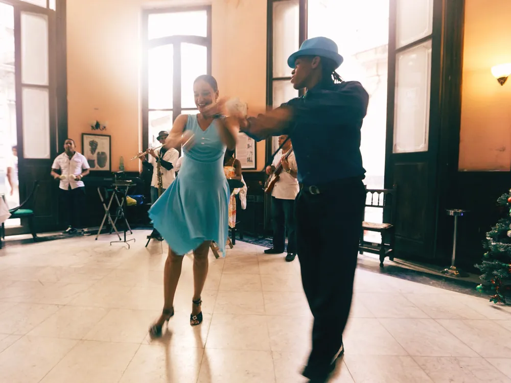 A couple mid-turn in a high-ceilinged room with a band behind them
