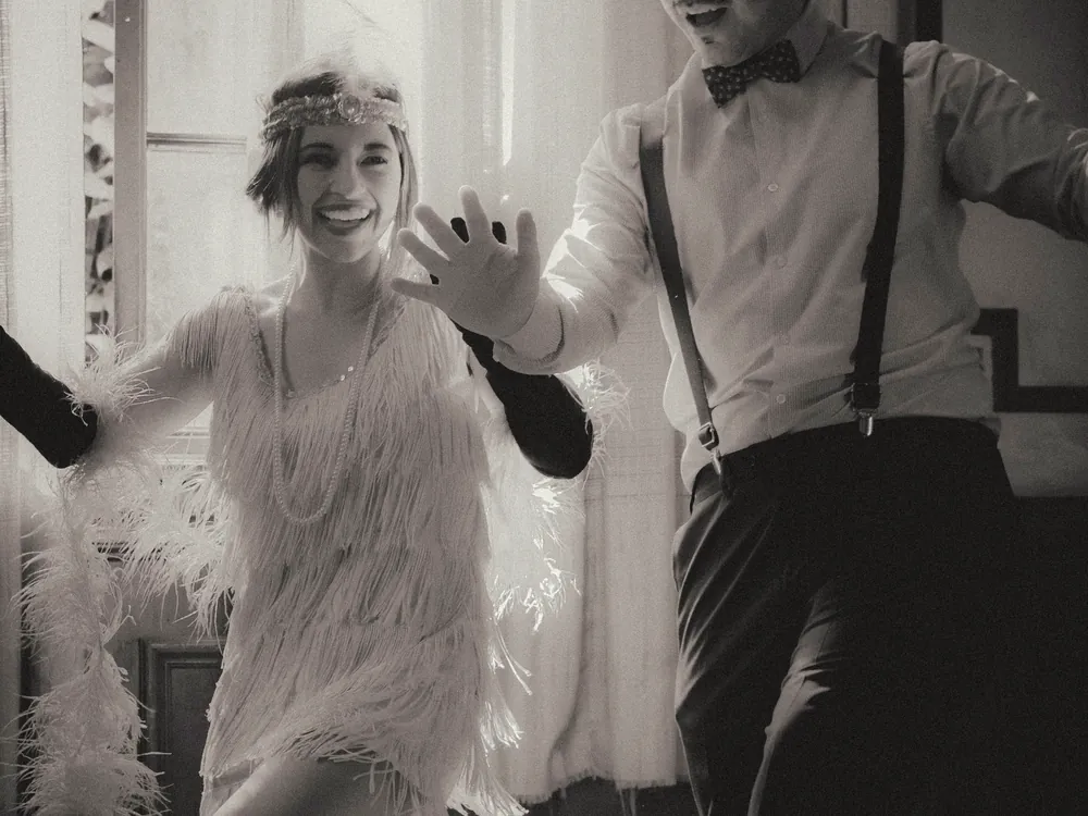 A couple dancing a lively step by a window, black and white