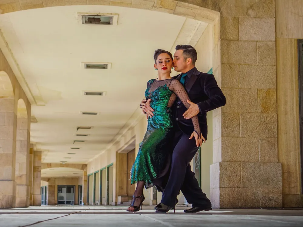 A couple in tango hold under a stone arcade