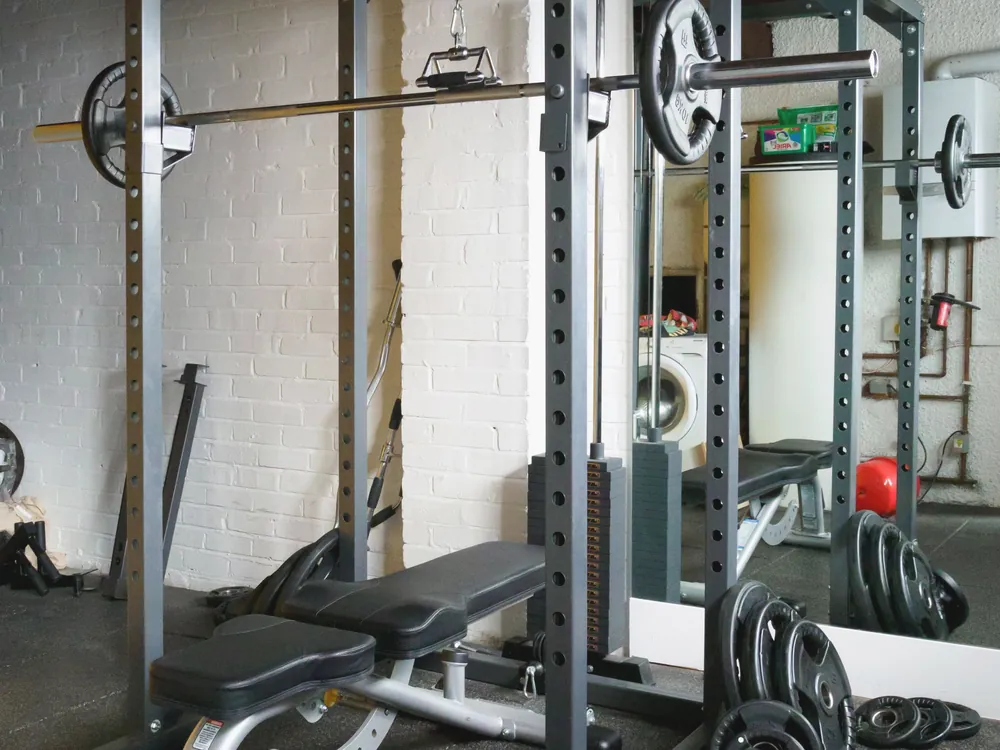 A power rack with a loaded bar and an adjustable bench