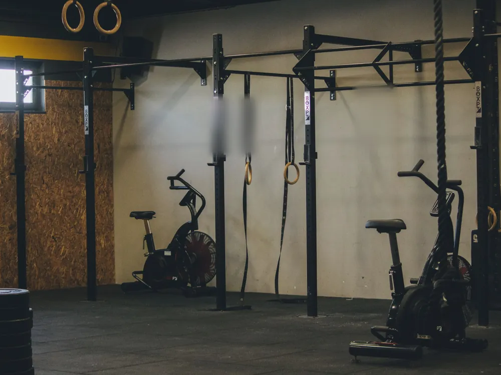 A row of training rigs with rings and air bikes