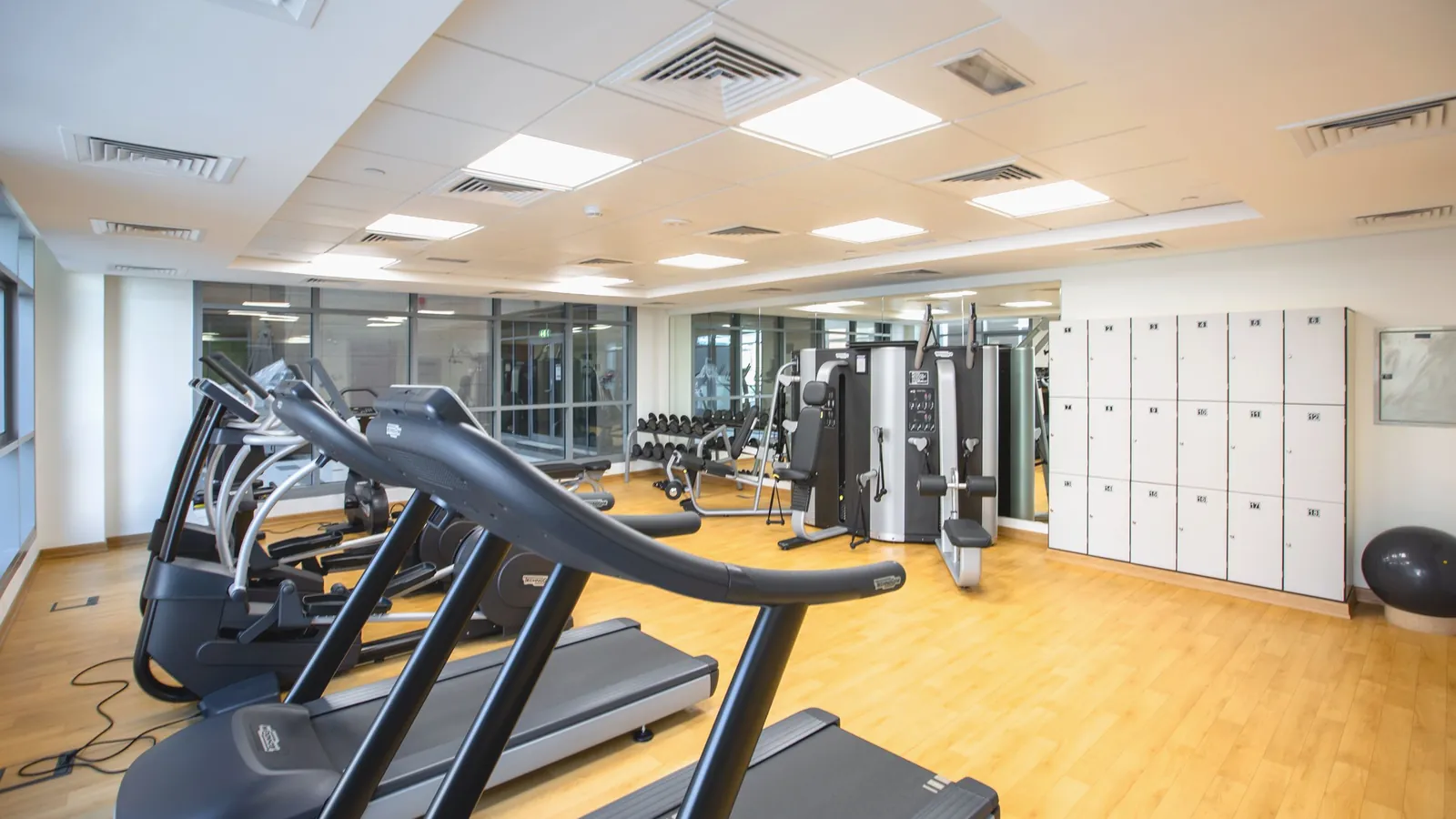 A bright gym floor with treadmills and lockers