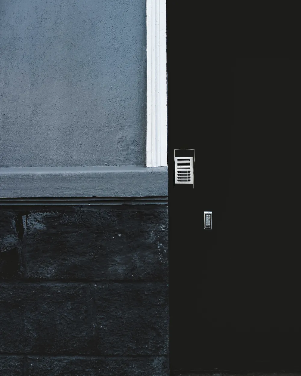 A dark door with a keypad and an intercom
