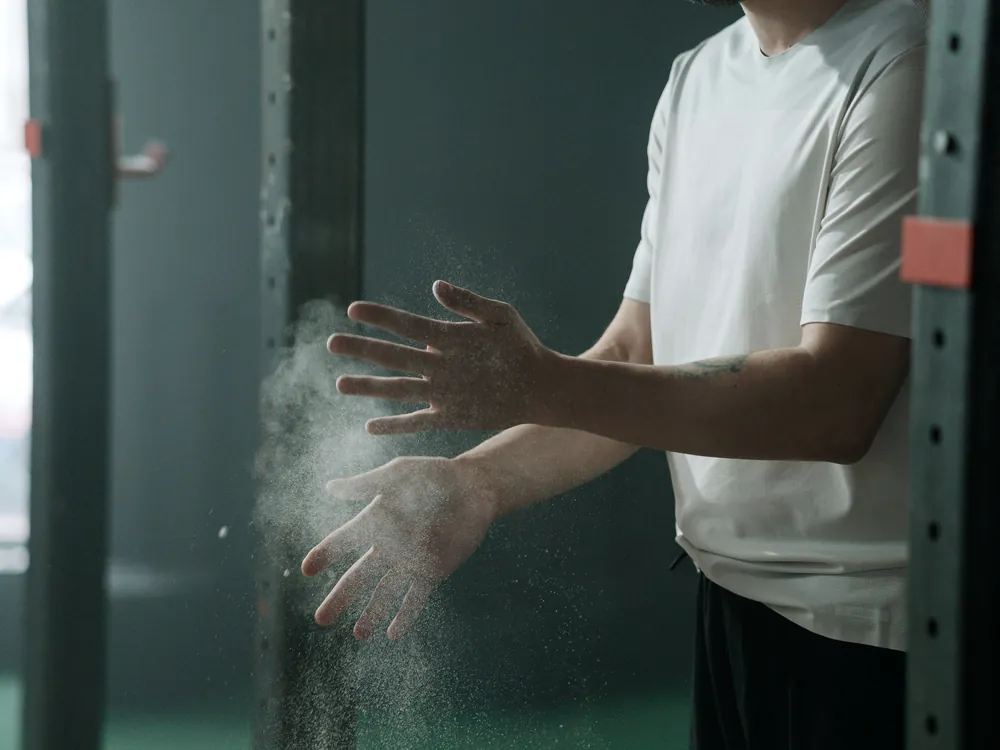 A lifter chalking his hands beside a rack