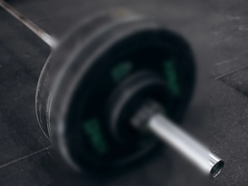 A loaded barbell at rest on a black floor