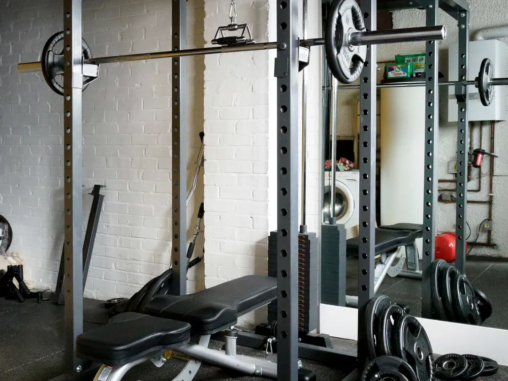 A power rack with a loaded bar and a bench