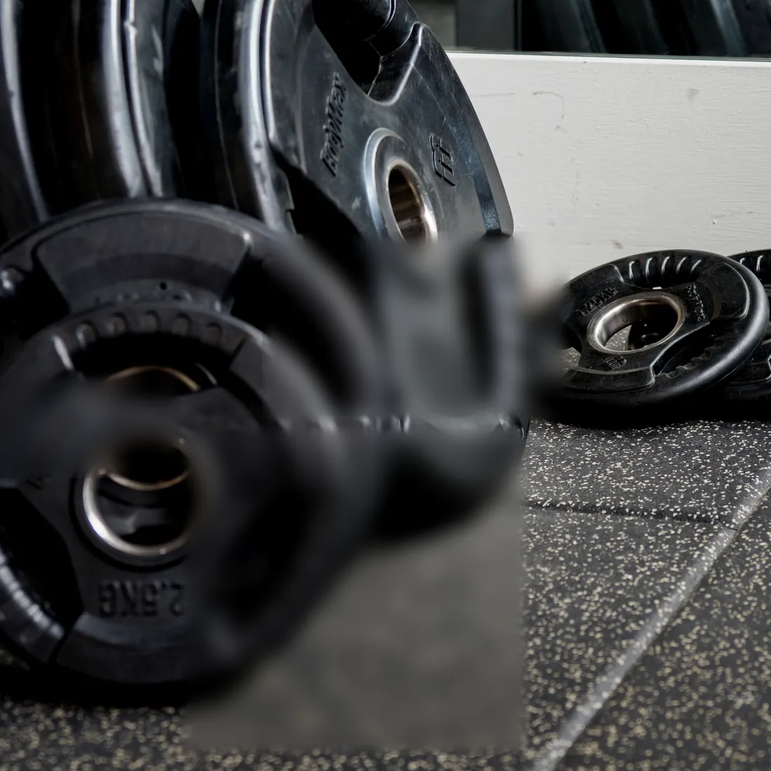 Iron plates stacked against a wall on rubber flooring