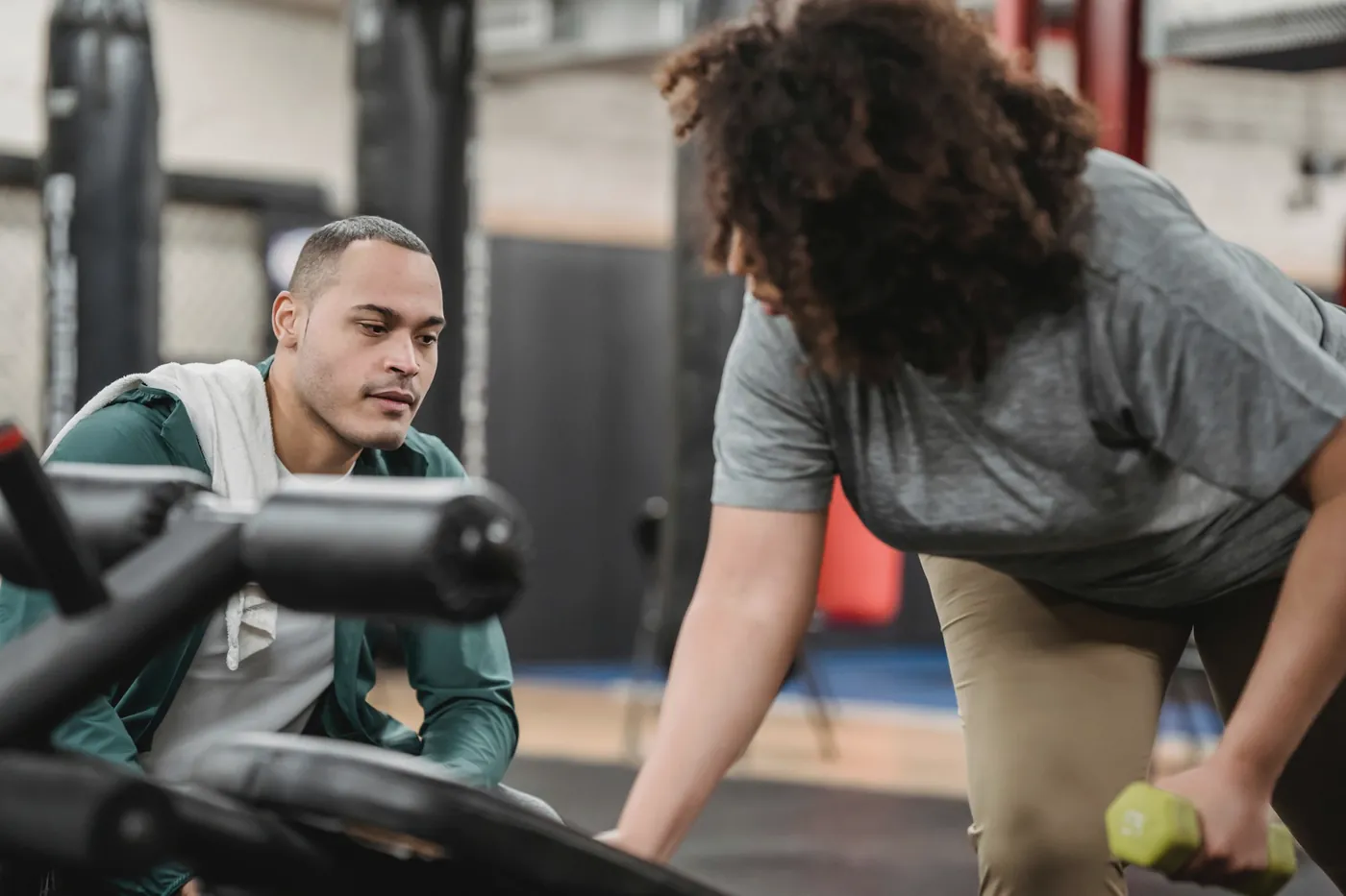 A trainer watching a client lift a light dumbbell