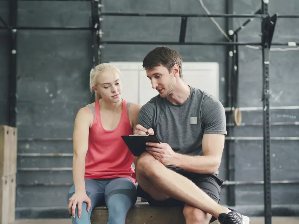 A trainer and a client sitting together going through notes