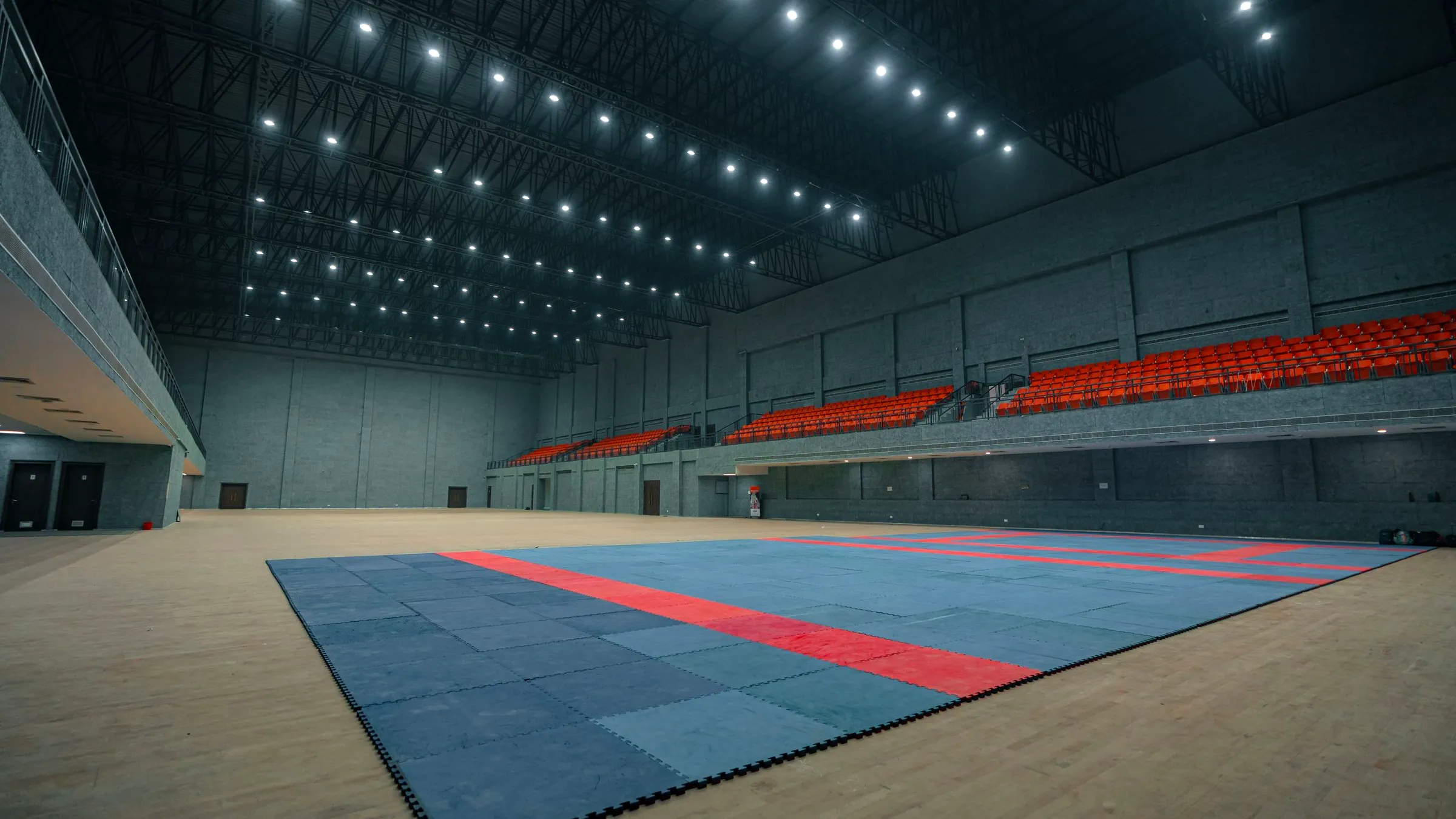 An empty competition floor in a large hall, the stands empty