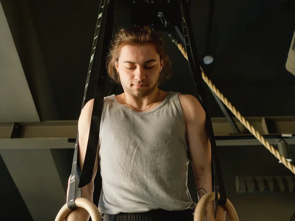 An adult in a grey vest holding a pair of wooden rings