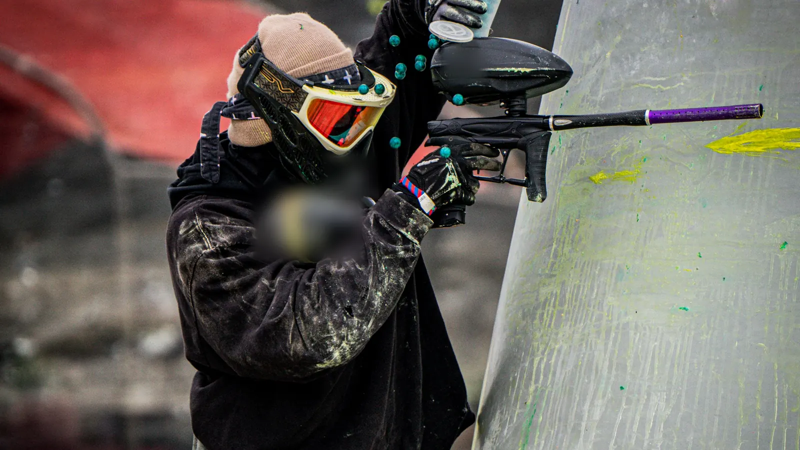 A masked adult player behind a paint-marked inflatable bunker