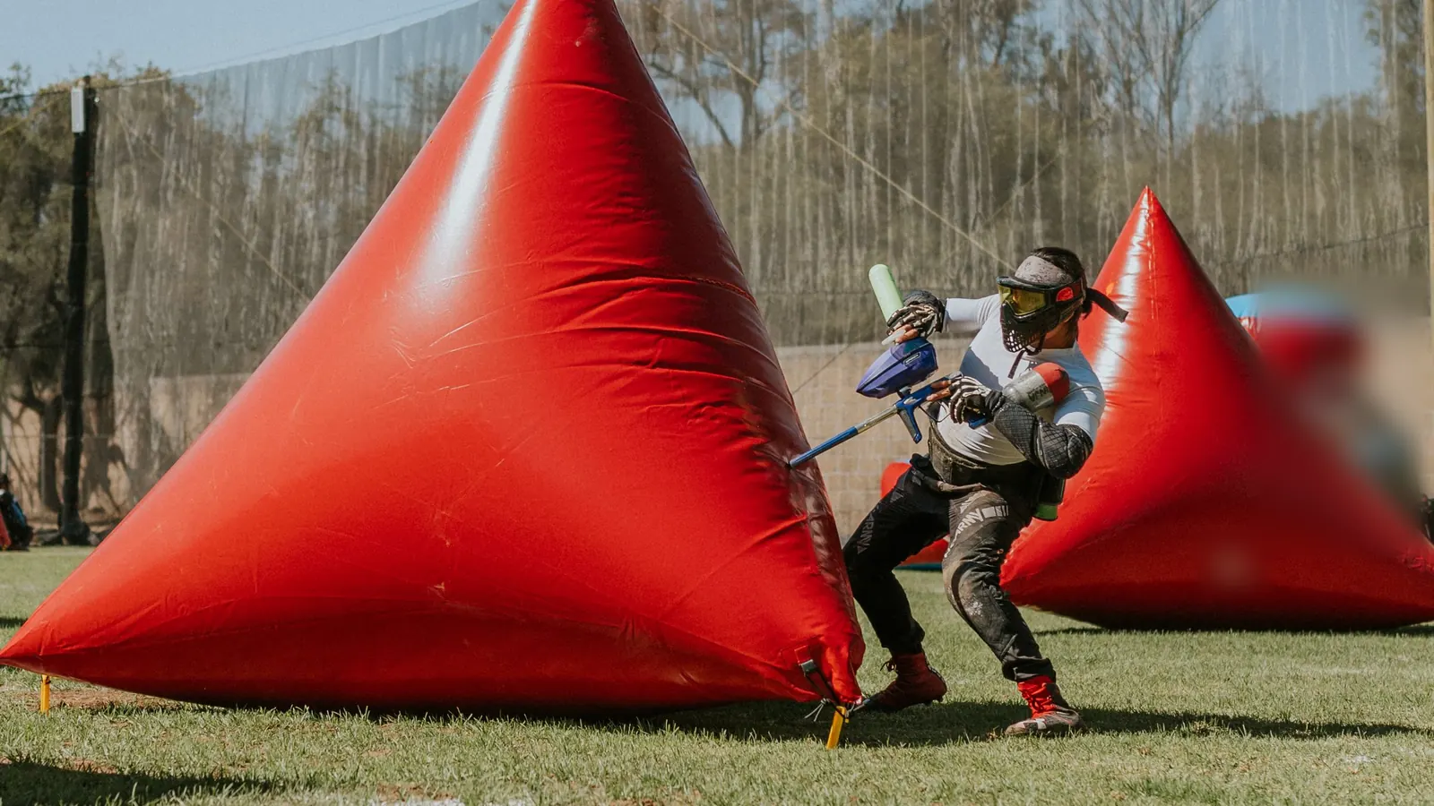 A masked adult player moving between two triangular inflatable bunkers