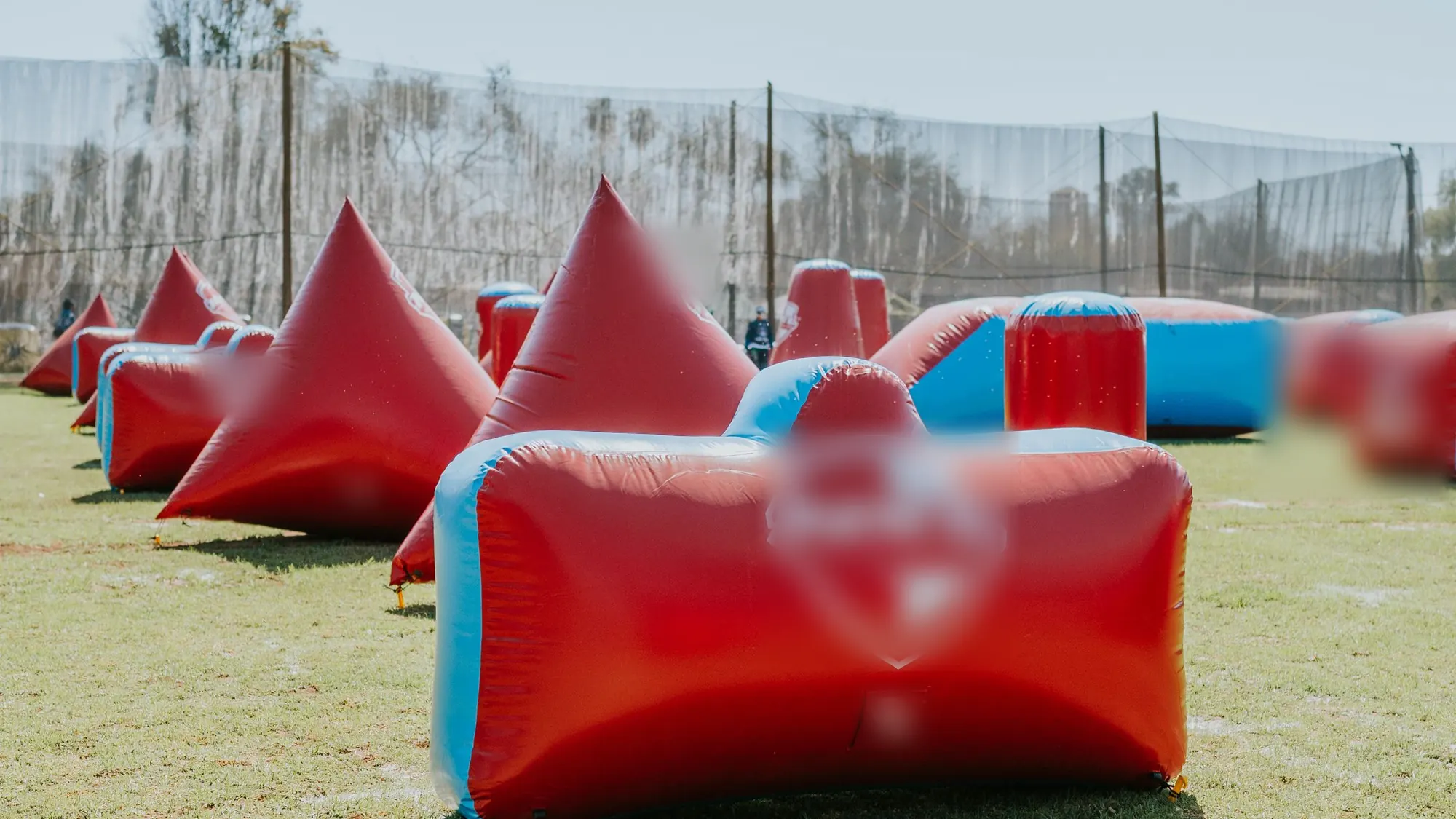 An inflatable tournament-layout field, empty, behind netting