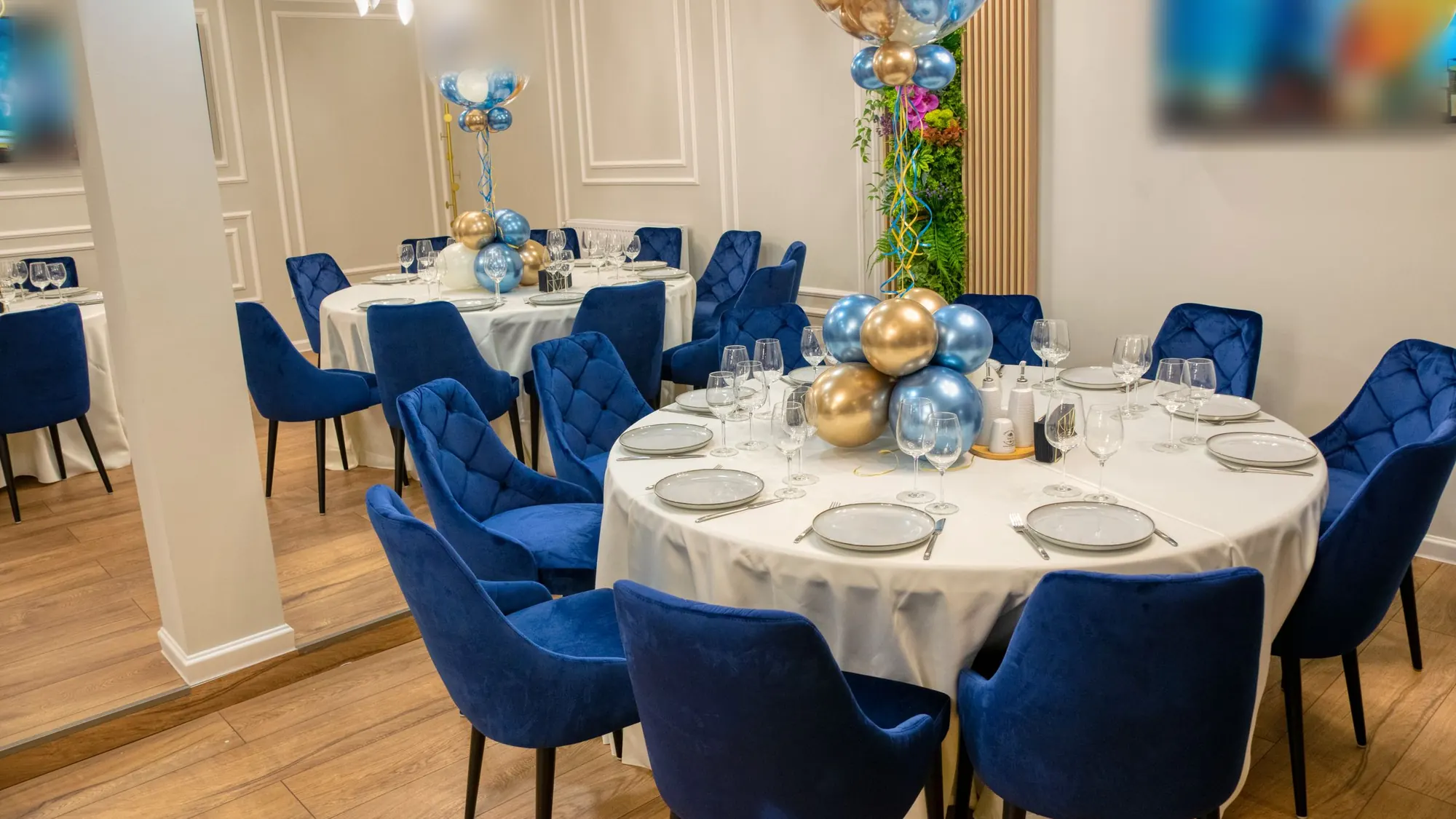 A party room laid for a group, round tables and balloons, no people