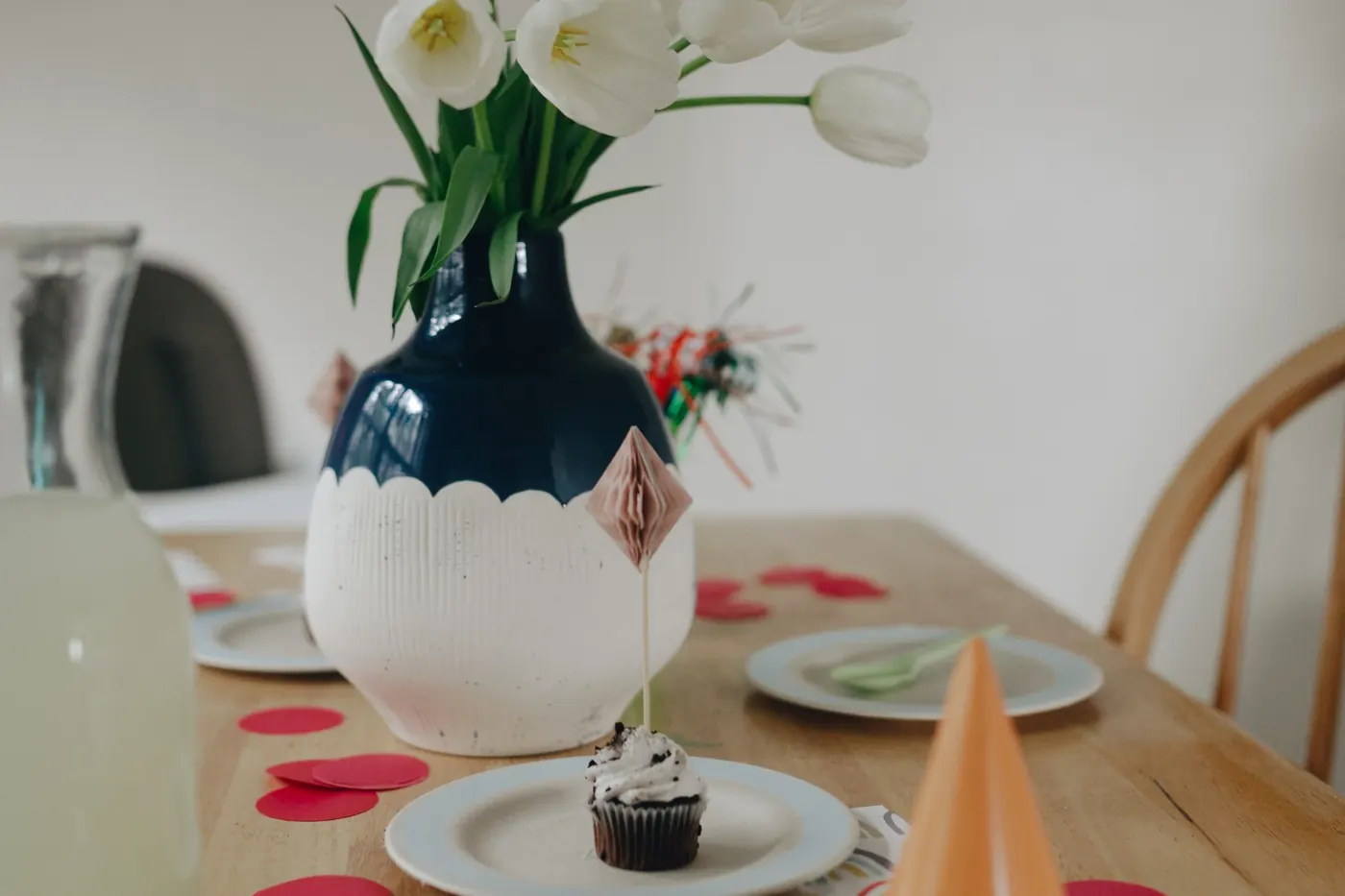 A laid party table with flowers, plates and a party hat, no people